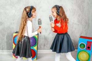 Funny kids singing and listening to music on headphones. The concept is childhood, lifestyle, dance, music.