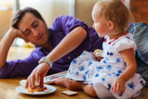 Happy family of father and his adorable little daughter playing together at home