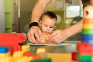 Little child and father are drawing on a paper. Kindergarten concept.