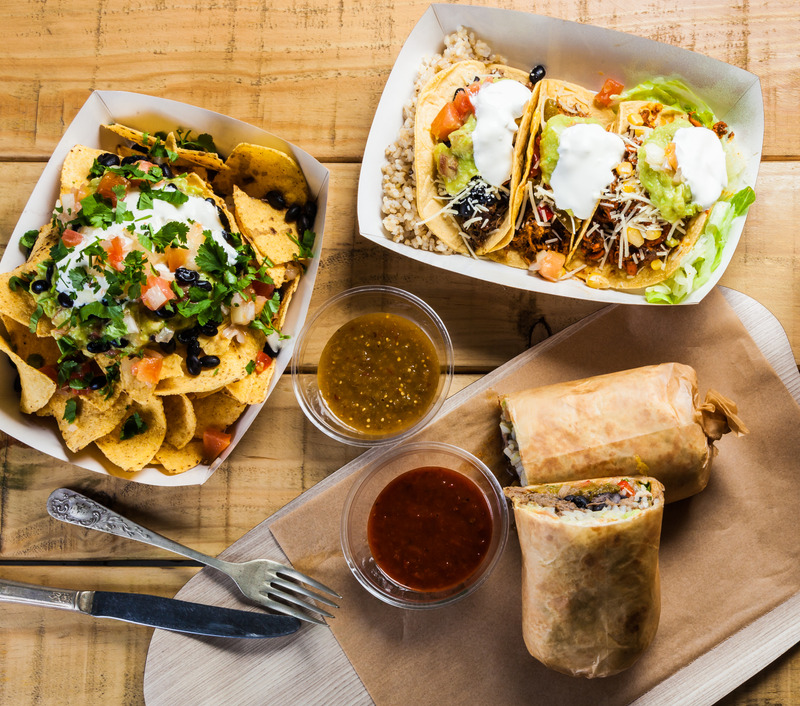 Takeaway Mexican food: burrito, nachos, tacos and spicy sauce.