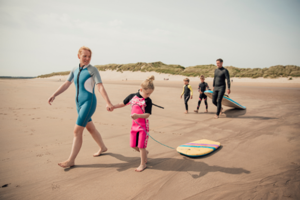 family together on a surfing holiday in wetsuits