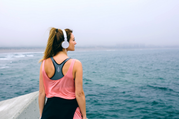 woman with headphones staring at the ocean